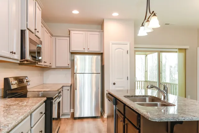 a kitchen with granite countertop kitchen island stainless steel appliances a sink stove and refrigerator
