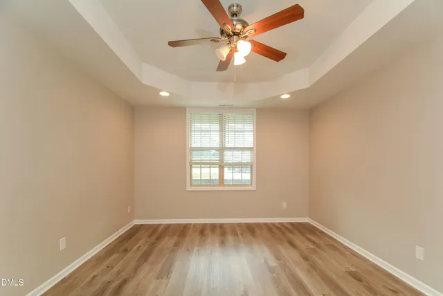 an empty room with wooden floor fan and windows