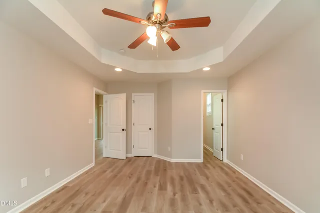 an empty room with chandelier fan and windows