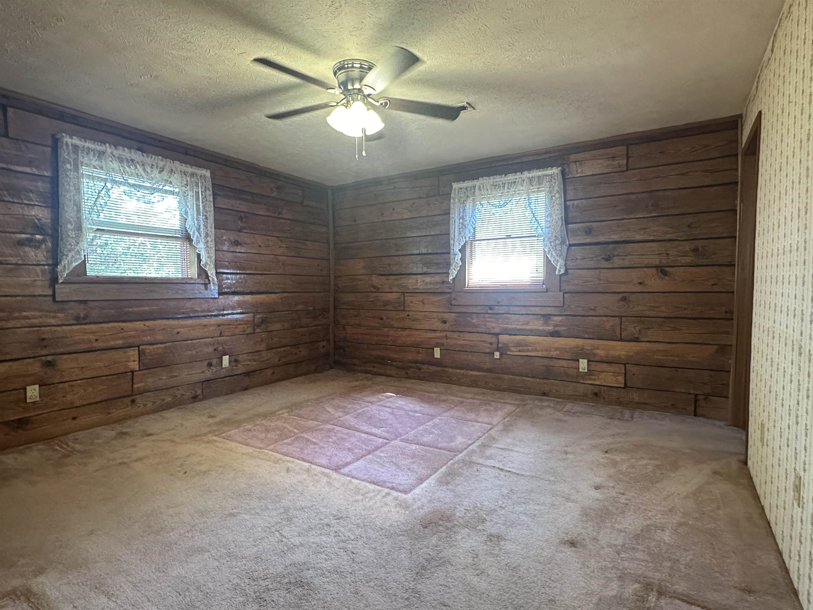 7148 Leapwood Enville Road Adamsville, TN 38310 - Photo 15 of 31 Spare room with wood walls, ceiling fan, light colored carpet, and a textured ceiling