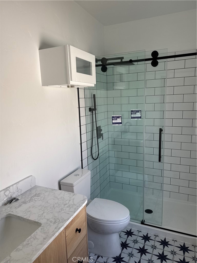 4193 5th Street Riverside, CA 92501 - Photo 28 of 33 a bathroom with a granite countertop toilet a sink a shower and mirror