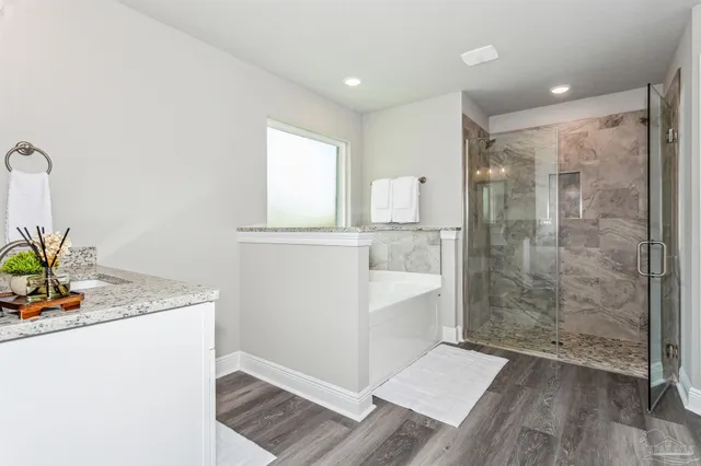 a bathroom with a granite countertop sink a mirror and shower