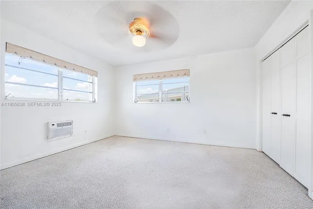 an empty room with windows and ceiling fan