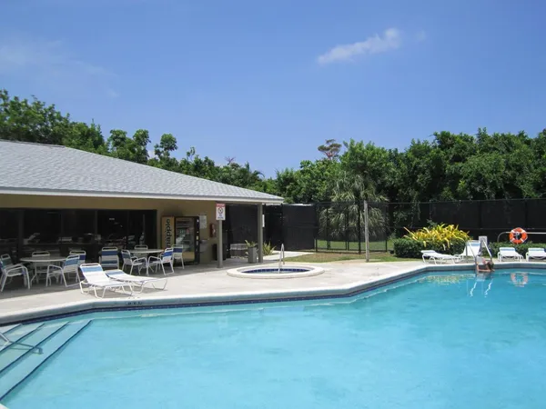 a view of swimming pool with seating area and trees in the background
