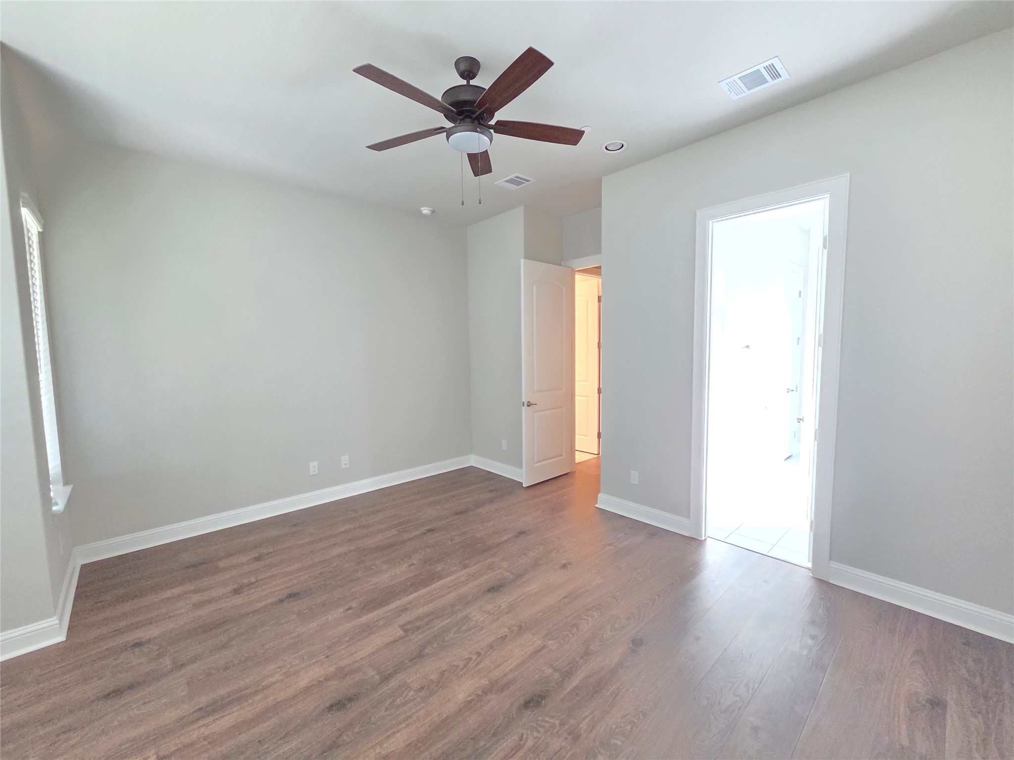 600 C-Bar Ranch Trail, Unit 121 Cedar Park, TX 78613 - Photo 17 of 32 Rich wood flooring grounds this airy bedroom, illuminated by natural light and a ceiling fan.
