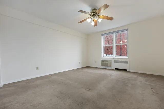 an empty room with chandelier fan and windows