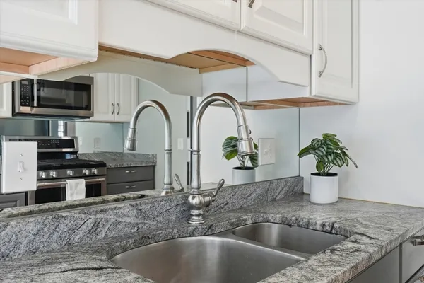 a kitchen with stainless steel appliances granite countertop a sink a stove and cabinets