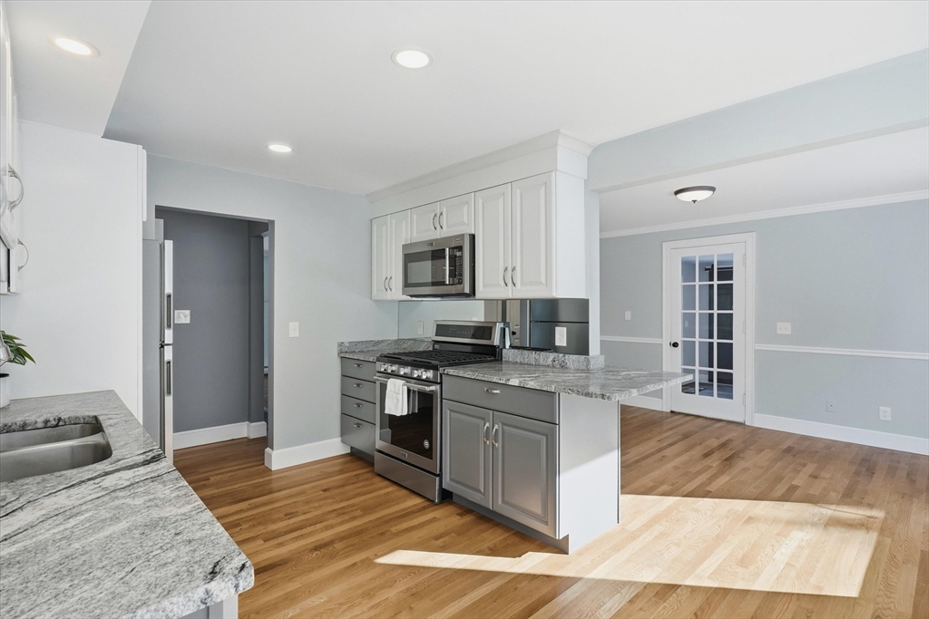 11 West Bradstreet Road North Andover, MA 01845 - Photo 10 of 42 a large kitchen with stainless steel appliances granite countertop a stove top oven a sink dishwasher a dining table and chairs with wooden floor