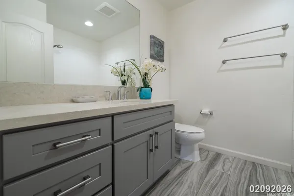 a bathroom with a granite countertop toilet sink and mirror