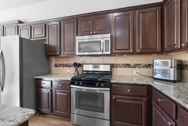a kitchen with granite countertop a stove top oven microwave and refrigerator