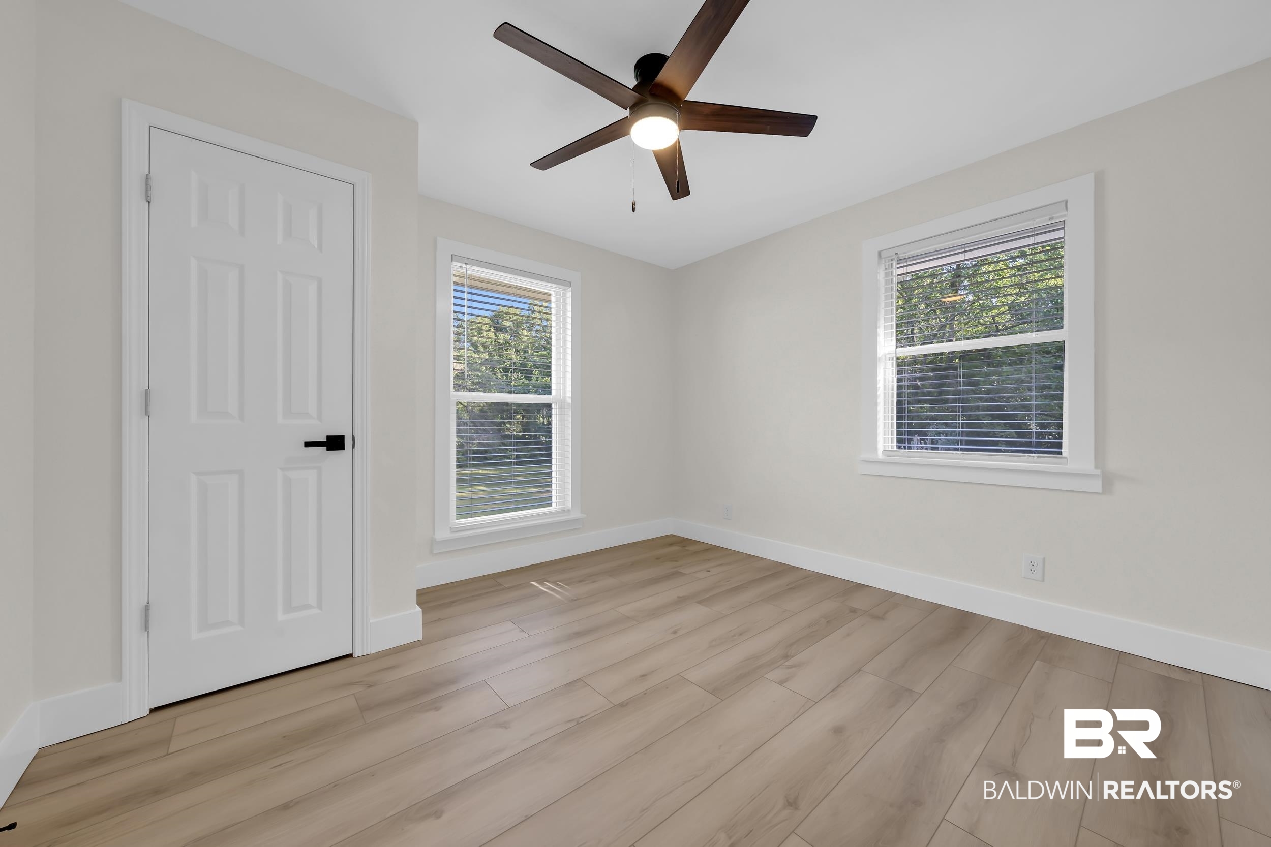 8170 Wilmer Georgetown Road Wilmer, AL 36587 - Photo 16 of 31 Spacious room featuring wood-finish flooring, two windows with blinds, a ceiling fan with integrated lighting, and a paneled door with matte black hardware