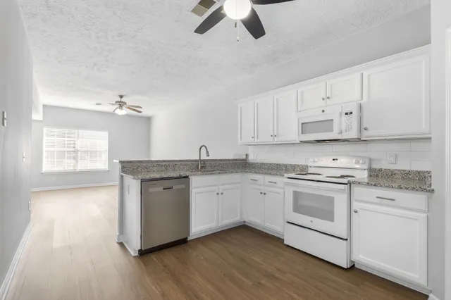 a kitchen with granite countertop white cabinets and white appliances