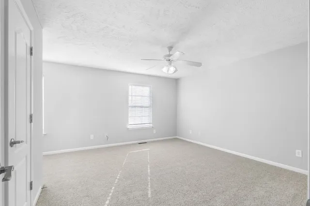 an empty room with windows and chandelier fan