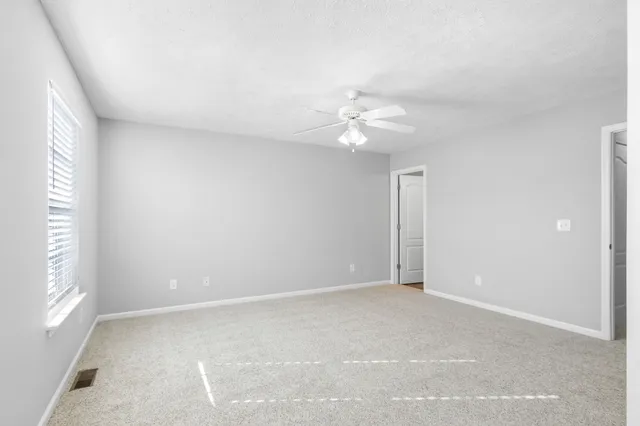an empty room with windows and fan