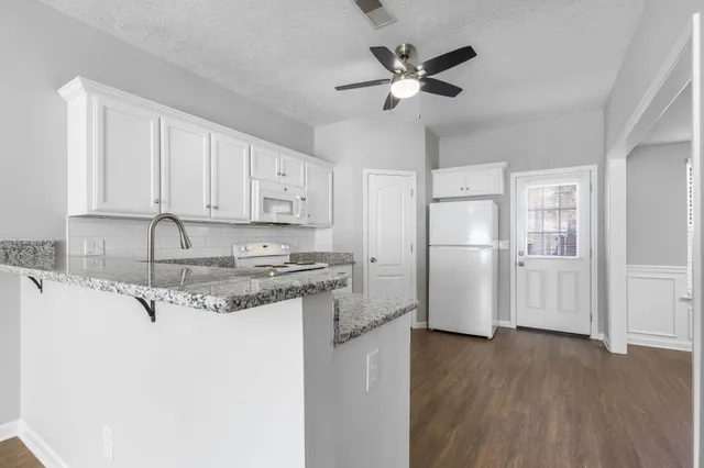 a kitchen with stainless steel appliances granite countertop a refrigerator a sink and white cabinets