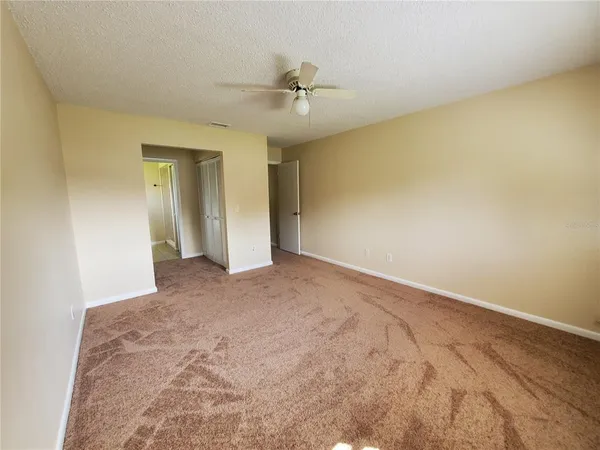 an empty room with a chandelier fan and closet