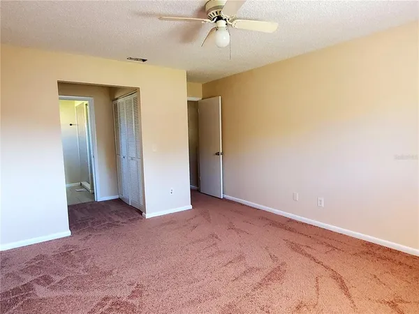 an empty room with a ceiling fan and closet area