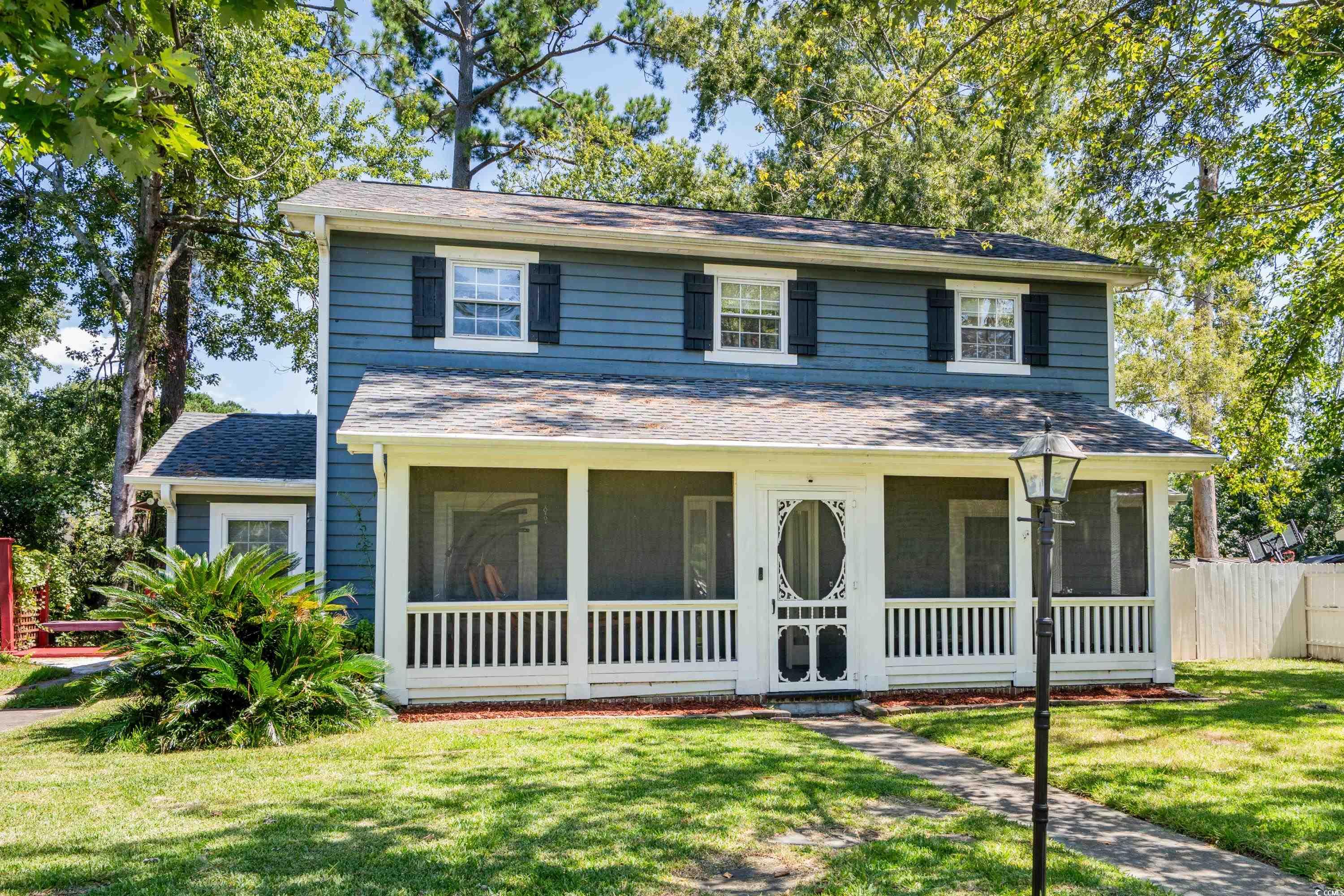 Traditional-style home featuring a front lawn, a sunroom, and a shingled roof