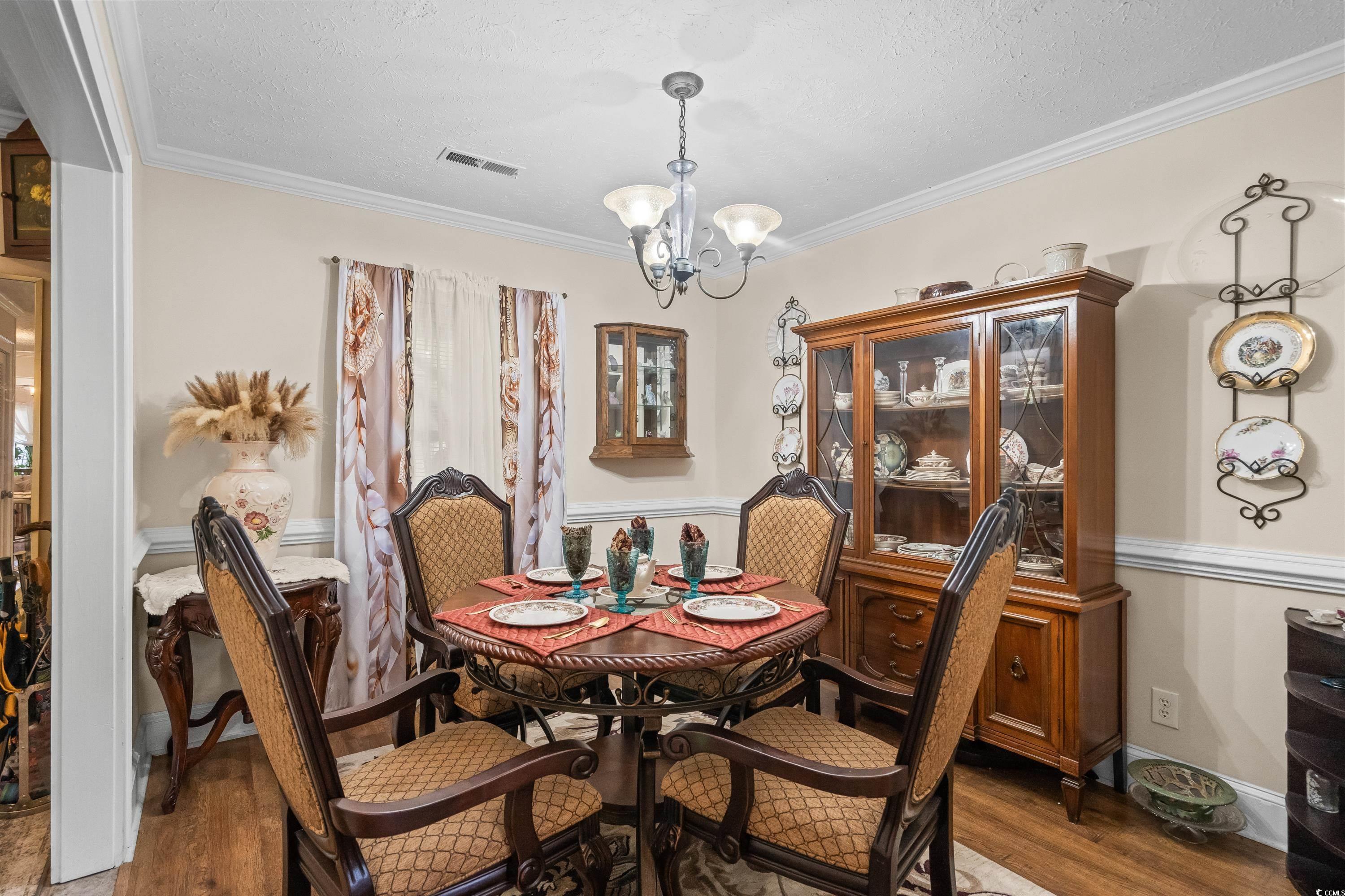 159 Brookgate Drive Myrtle Beach, SC 29579 - Photo 5 of 40 Dining space featuring crown molding, a textured ceiling, a chandelier, and wood finished floors