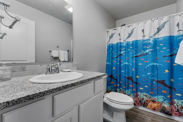 a bathroom with a granite countertop toilet sink and mirror