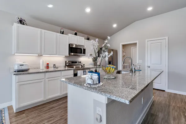 a kitchen with granite countertop a sink a counter top space appliances and cabinets