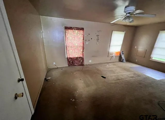 a view of a room with a ceiling fan and window