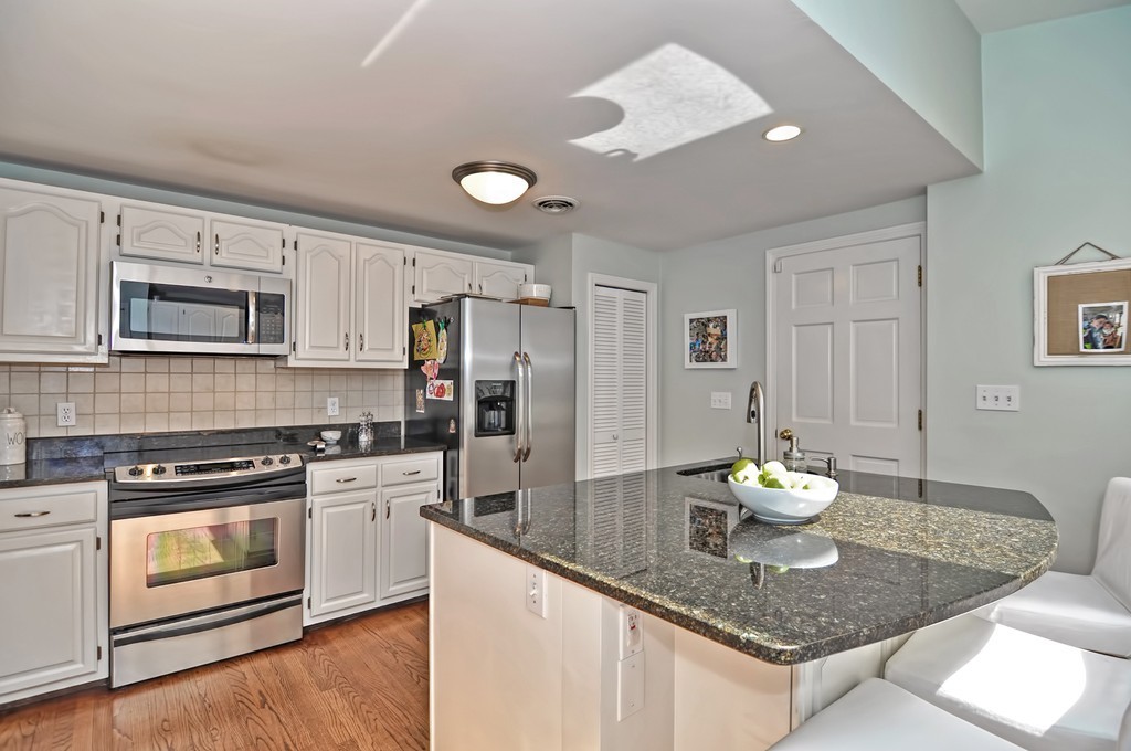 10 Pilgrim Road Wellesley, MA 02481 - Photo 4 of 25 a kitchen with stainless steel appliances kitchen island granite countertop a stove a sink and white cabinets