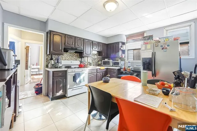 a kitchen with stainless steel appliances a sink a stove a refrigerator cabinets and a dining table