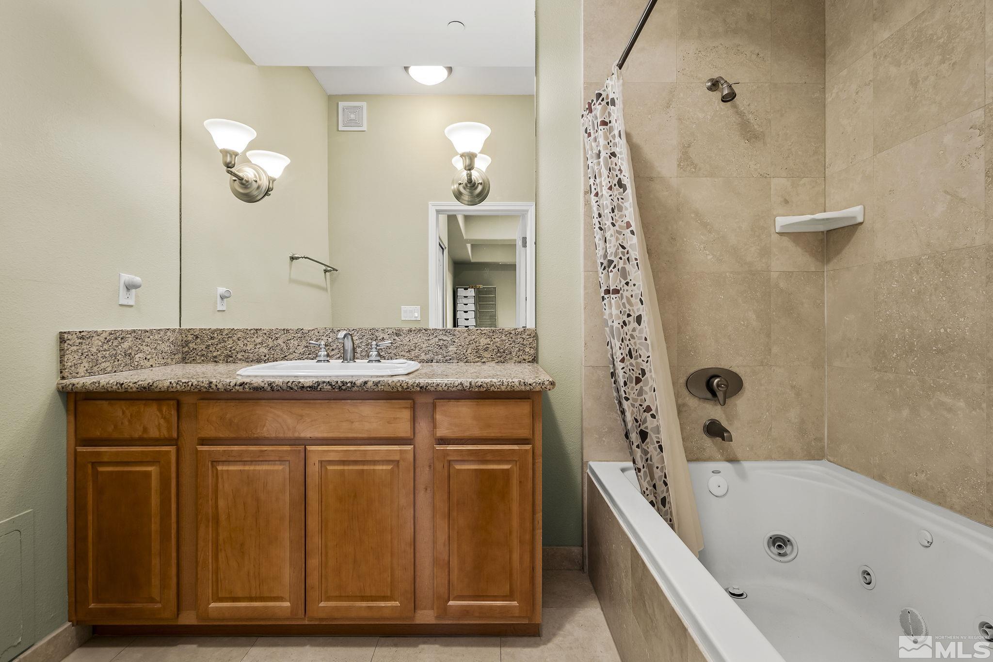 200 West 2nd Street, Unit 202 Reno, NV 89501 - Photo 14 of 18 a bathroom with a granite countertop sink a mirror a vanity and bathtub