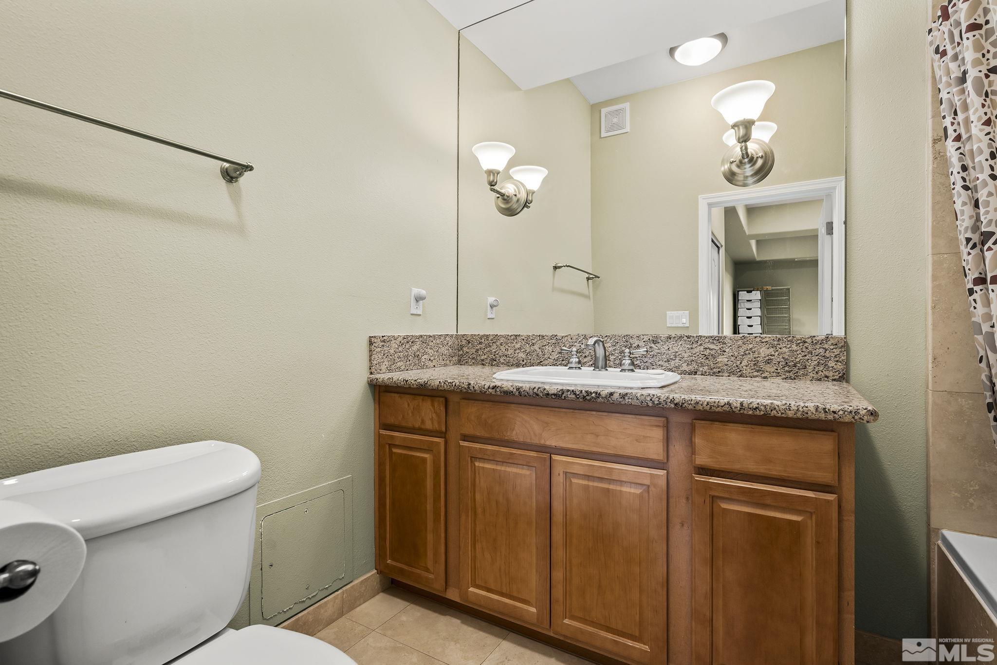 200 West 2nd Street, Unit 202 Reno, NV 89501 - Photo 15 of 18 a bathroom with a granite countertop sink a toilet and a mirror