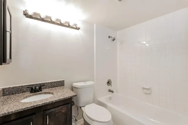 a bathroom with a granite countertop sink toilet and shower