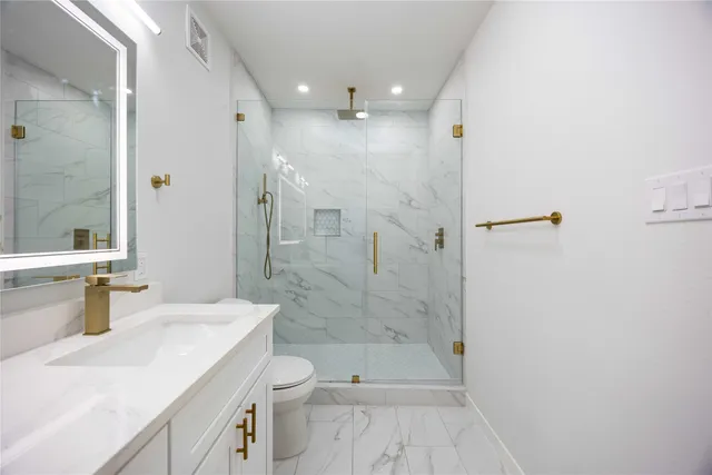 a bathroom with a sink a toilet a mirror and shower