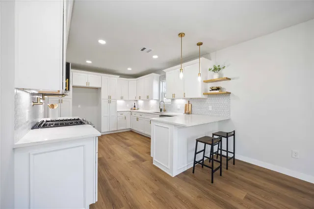 a kitchen with a sink a stove cabinets and wooden floor