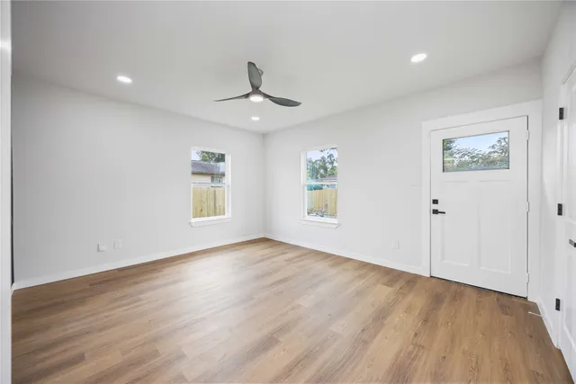 an empty room with wooden floor chandelier and windows