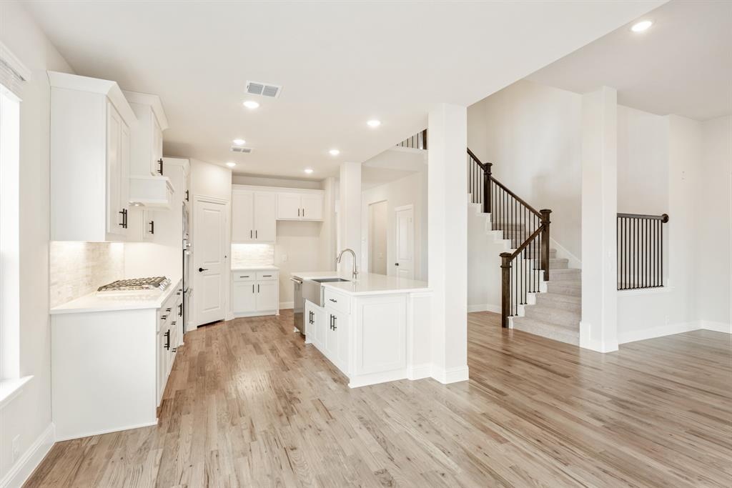 2304 Prosper Way Mansfield, TX 76063 - Photo 17 of 39 a large white kitchen with wooden floor and a sink