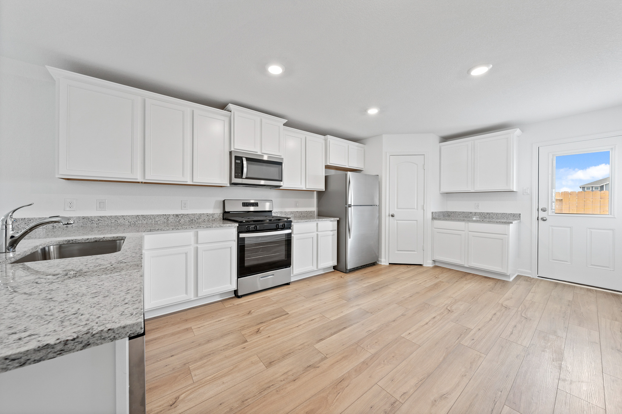 402 Aplite Pass Maxwell, TX 78656 - Photo 2 of 6 Kitchen featuring stainless steel appliances, white cabinets, light stone countertops, light wood-style floors, and recessed lighting