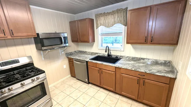 a kitchen with granite countertop cabinets stainless steel appliances and a sink