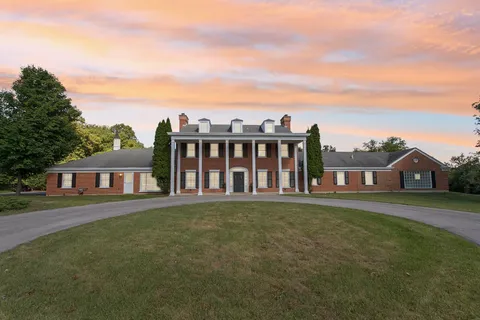 a view of a house with a big yard and large trees