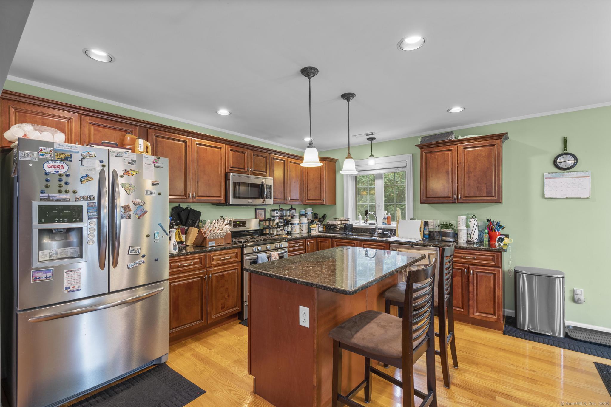 55 Allen Street New Britain, CT 06053 - Photo 23 of 40 a kitchen with stainless steel appliances granite countertop a stove refrigerator a sink dishwasher a dining table and chairs with wooden floor
