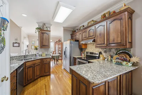 a kitchen with stainless steel appliances granite countertop a refrigerator a stove top oven and sink