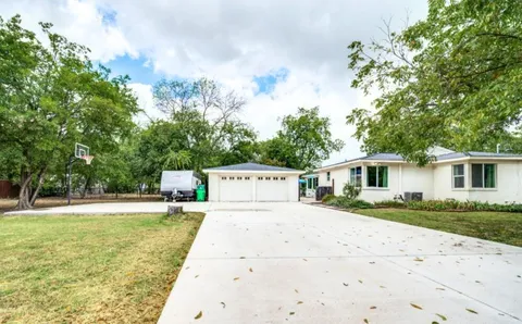 a view of a house with a yard and large trees