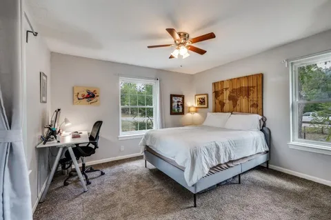 a bedroom with a bed a chandelier and windows
