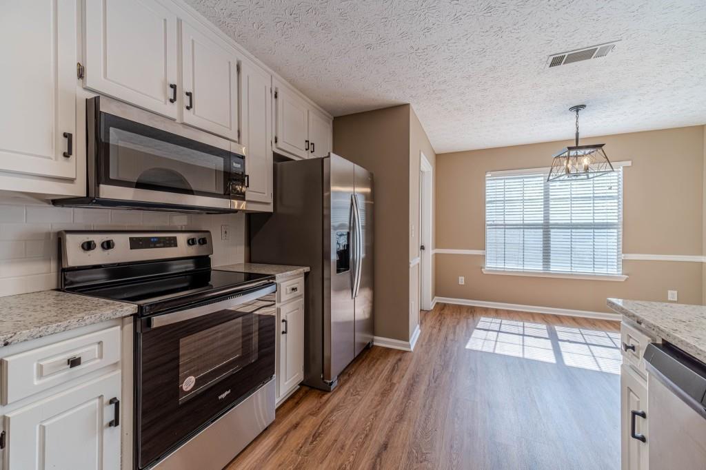 701 Woodland Ridge Drive Monroe, GA 30656 - Photo 14 of 39 a kitchen with granite countertop wooden floors appliances and cabinets