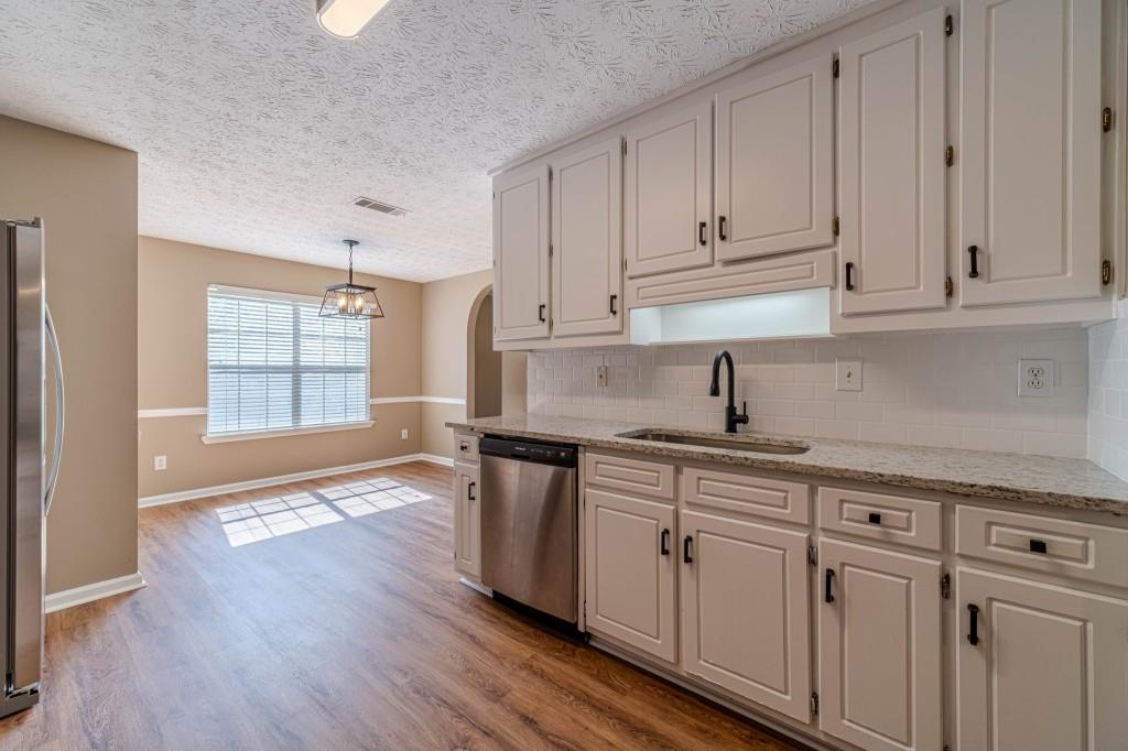 701 Woodland Ridge Drive Monroe, GA 30656 - Photo 15 of 39 a kitchen with stainless steel appliances granite countertop a sink dishwasher a stove and white cabinets with wooden floor