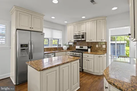 a kitchen with granite countertop a stove a sink and a refrigerator