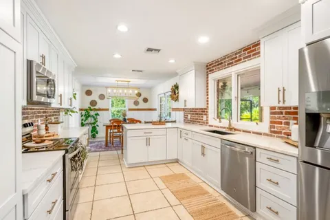 a kitchen with stainless steel appliances kitchen island granite countertop a refrigerator and a stove top oven