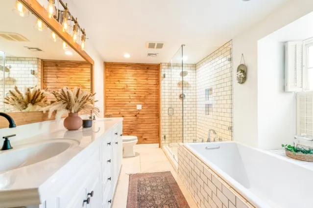 a bathroom with a granite countertop tub sink and large mirror