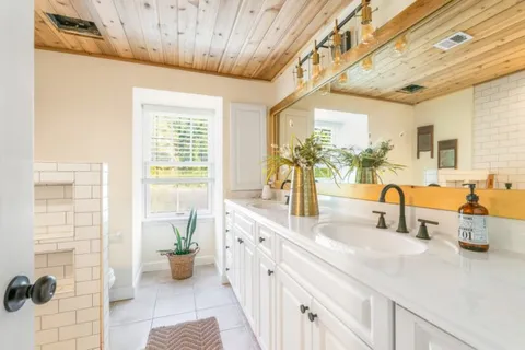 a bathroom with a double vanity sink a mirror and a shower