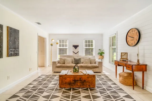 a living room with furniture a clock on wall and a window
