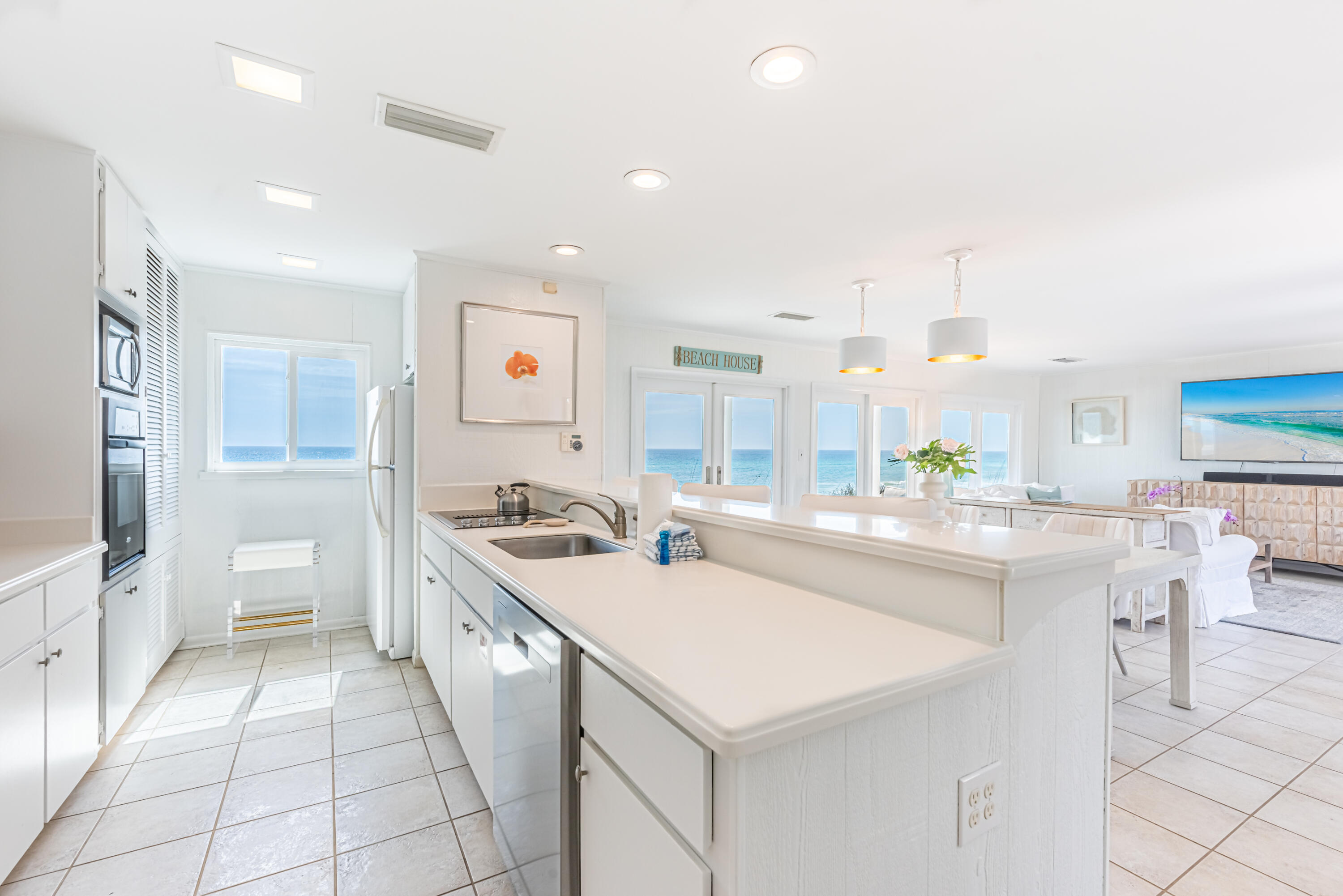 4731 West County Highway 30A Santa Rosa Beach, FL 32459 - Photo 15 of 44 a large white kitchen with a white countertops a stove a dining table and chairs
